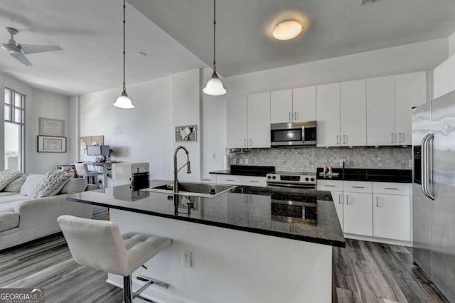 kitchen with hardwood / wood-style flooring, appliances with stainless steel finishes, hanging light fixtures, and white cabinetry