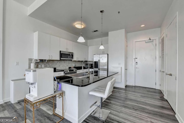 kitchen featuring white cabinets, sink, a kitchen island with sink, stainless steel appliances, and a breakfast bar area