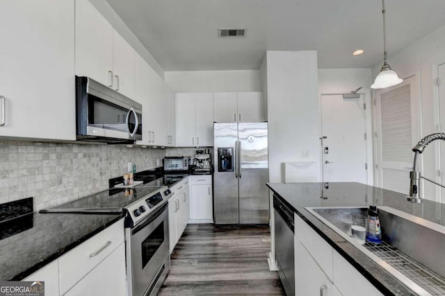 kitchen featuring pendant lighting, dark wood-type flooring, sink, stainless steel appliances, and white cabinets