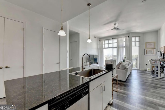 kitchen with hanging light fixtures, sink, stainless steel dishwasher, white cabinetry, and dark stone countertops