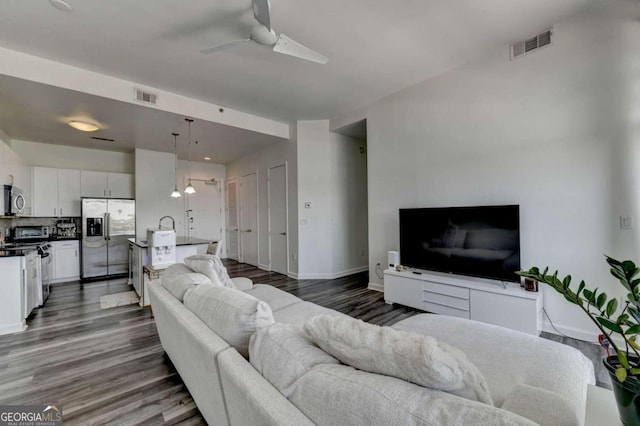 living room featuring ceiling fan, sink, and dark hardwood / wood-style flooring