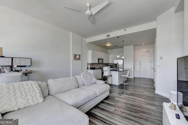 living room with dark wood-type flooring and ceiling fan