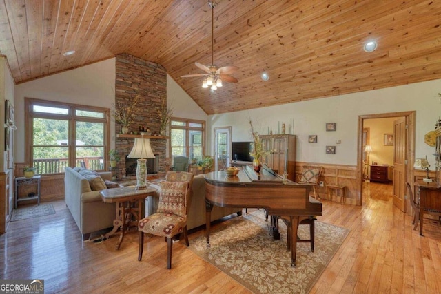 living room featuring wooden ceiling, high vaulted ceiling, light hardwood / wood-style flooring, and a stone fireplace