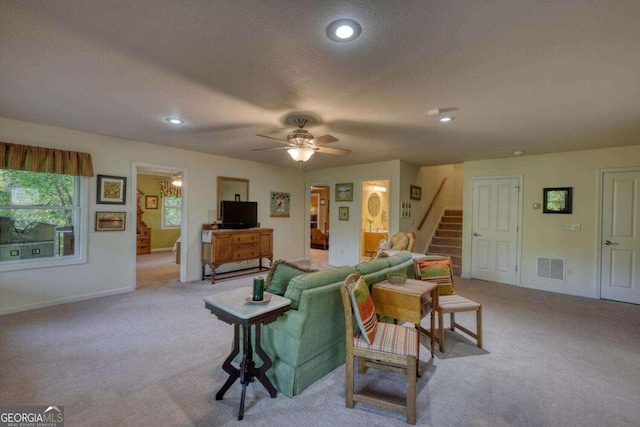 living room featuring light carpet, ceiling fan, and a textured ceiling