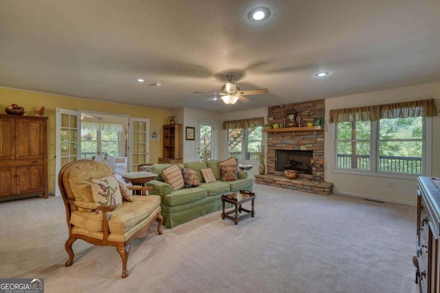 carpeted living room featuring ceiling fan, a textured ceiling, a fireplace, and french doors