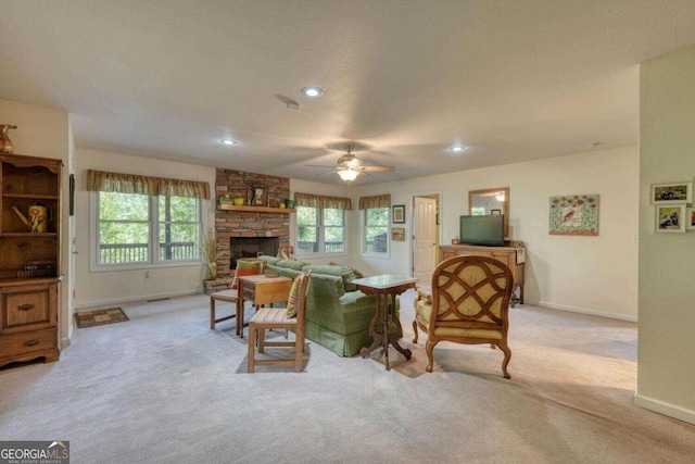 carpeted living room featuring a healthy amount of sunlight, ceiling fan, and a stone fireplace