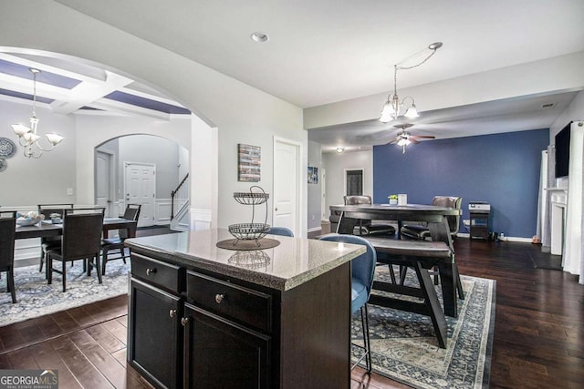 kitchen featuring pendant lighting, ceiling fan with notable chandelier, a kitchen island, coffered ceiling, and dark hardwood / wood-style floors