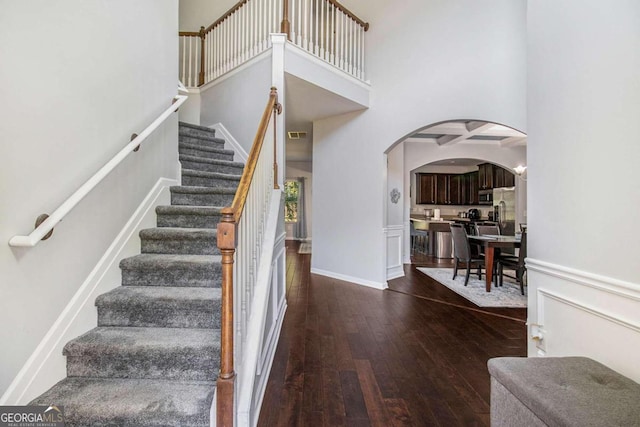 stairs with a towering ceiling and hardwood / wood-style floors