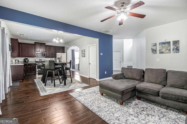 living room featuring ceiling fan with notable chandelier and dark hardwood / wood-style floors