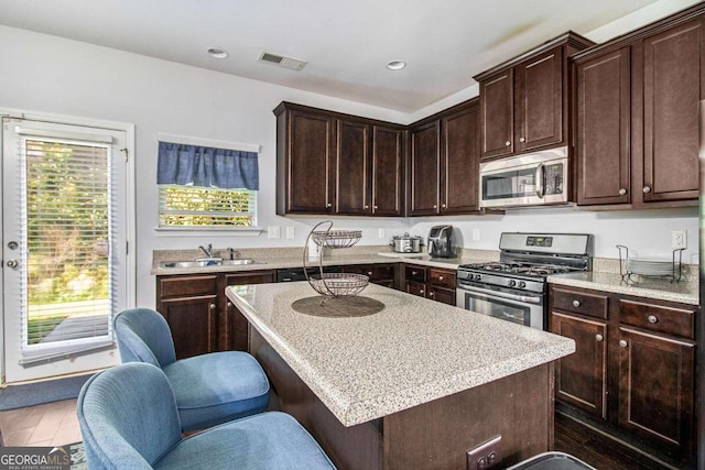 kitchen featuring dark brown cabinets, stainless steel appliances, dark hardwood / wood-style floors, and a center island