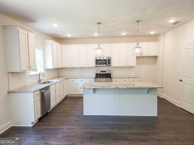 kitchen featuring pendant lighting, a center island, stainless steel appliances, and white cabinetry