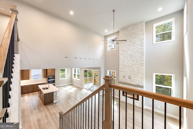 living room featuring a high ceiling, light wood-type flooring, plenty of natural light, and ceiling fan