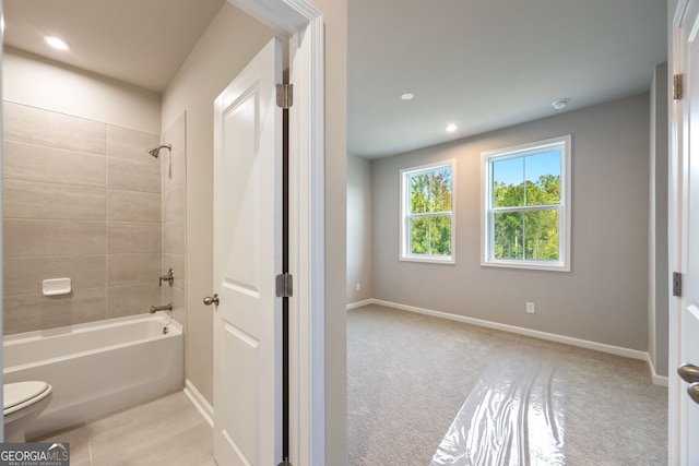 bathroom featuring tiled shower / bath and toilet