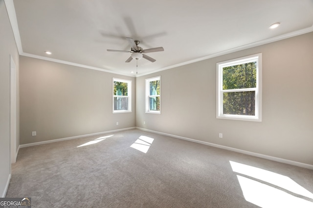 carpeted spare room featuring a healthy amount of sunlight, ceiling fan, and crown molding