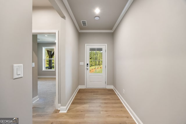 entryway with light wood-type flooring, a healthy amount of sunlight, and crown molding