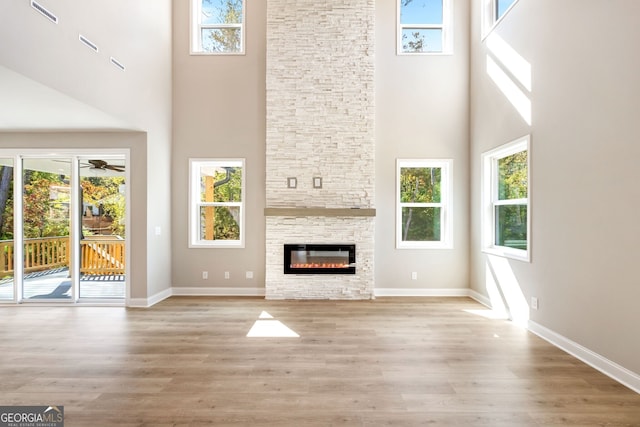 unfurnished living room with light hardwood / wood-style flooring, plenty of natural light, and a high ceiling