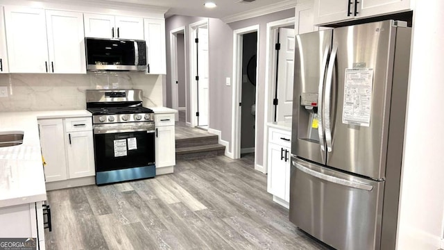 kitchen with appliances with stainless steel finishes, light hardwood / wood-style flooring, and white cabinetry