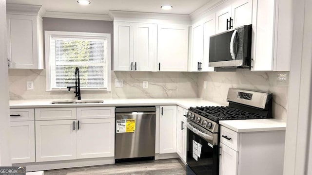 kitchen featuring ornamental molding, stainless steel appliances, sink, and white cabinetry