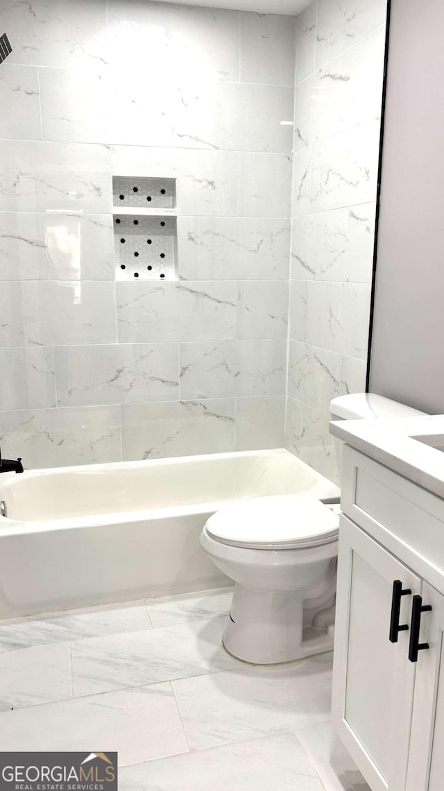 full bathroom featuring tiled shower / bath, vanity, and toilet