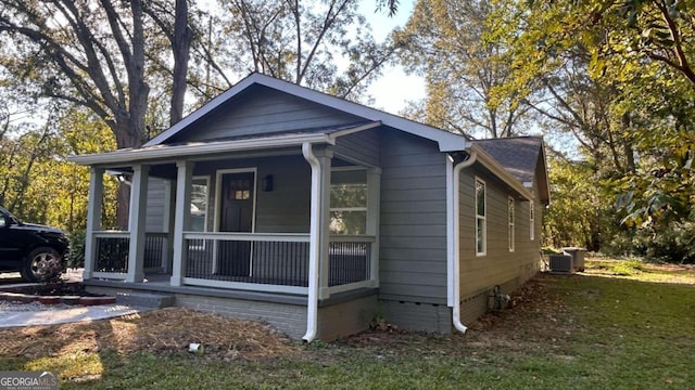 view of front of house with central AC, a front lawn, and covered porch