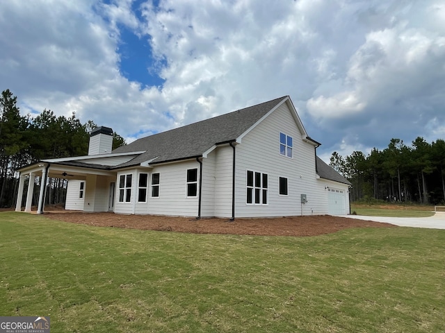 rear view of house with a garage and a lawn