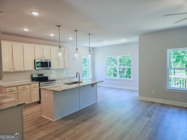 kitchen with sink, hanging light fixtures, stainless steel appliances, an island with sink, and white cabinets