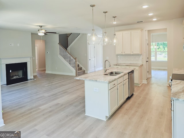 kitchen featuring decorative light fixtures, a center island with sink, white cabinetry, and sink