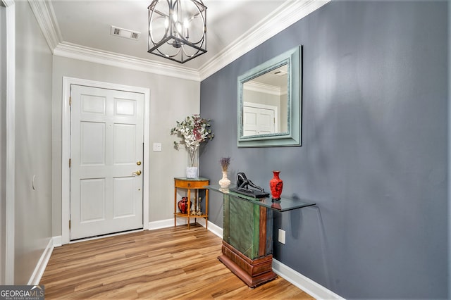 entrance foyer featuring a notable chandelier, ornamental molding, and hardwood / wood-style floors