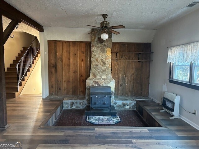 interior space with a textured ceiling, heating unit, ceiling fan, hardwood / wood-style flooring, and lofted ceiling