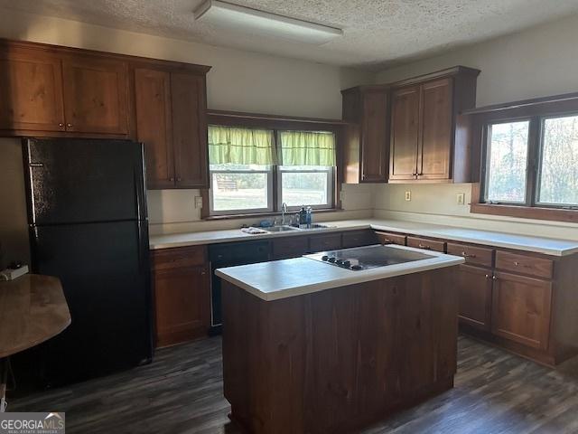 kitchen featuring black appliances, a healthy amount of sunlight, a kitchen island, and sink