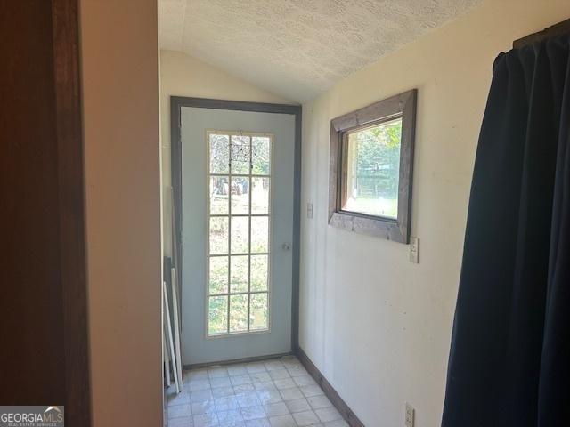 doorway to outside featuring lofted ceiling and a textured ceiling