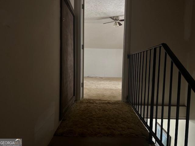 corridor featuring a textured ceiling and light carpet