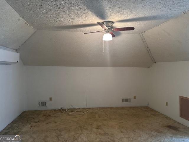 bonus room featuring ceiling fan, a wall unit AC, carpet floors, lofted ceiling, and a textured ceiling