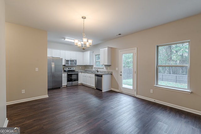 kitchen featuring stainless steel appliances, dark wood-type flooring, an inviting chandelier, white cabinets, and hanging light fixtures