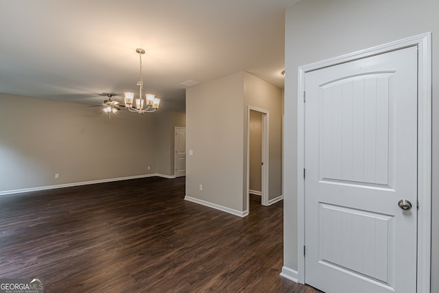 empty room with ceiling fan with notable chandelier and dark wood-type flooring