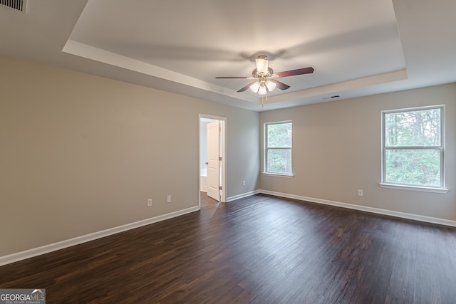 unfurnished room featuring ceiling fan, dark hardwood / wood-style flooring, and a tray ceiling