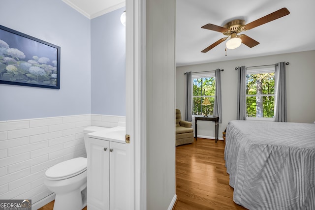 bedroom with light hardwood / wood-style floors, ornamental molding, tile walls, and ceiling fan