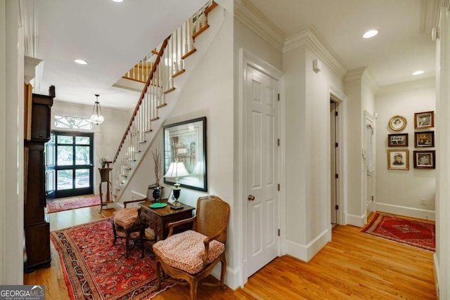 corridor featuring an inviting chandelier, light wood-type flooring, and ornamental molding