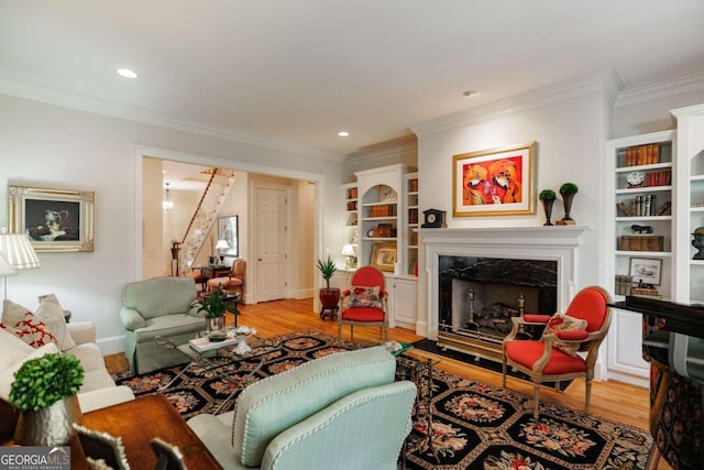 living room with ornamental molding, a high end fireplace, built in features, and light hardwood / wood-style flooring