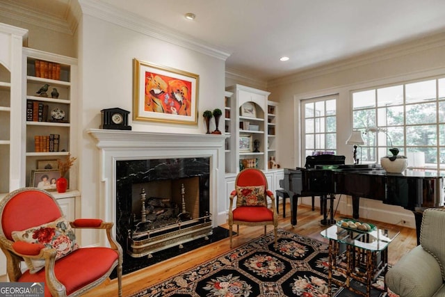 living area with wood-type flooring, ornamental molding, and a high end fireplace