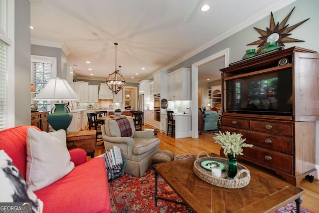 living room featuring ornamental molding, an inviting chandelier, and light hardwood / wood-style floors