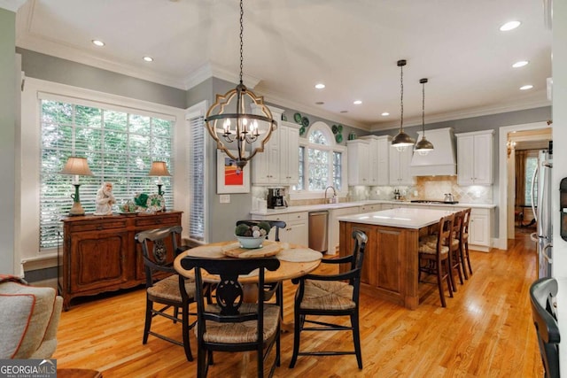 dining space featuring ornamental molding, a chandelier, sink, and light wood-type flooring