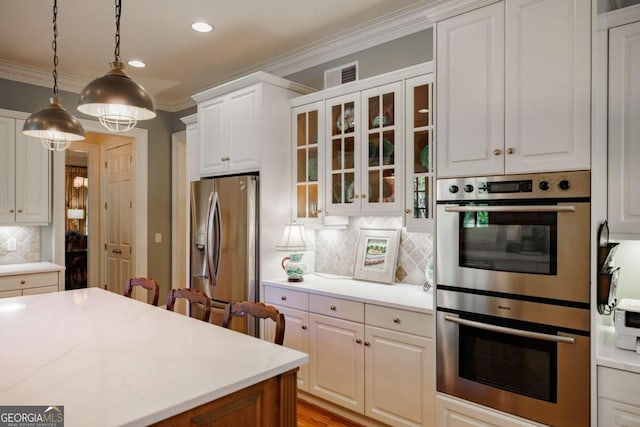 kitchen featuring hanging light fixtures, ornamental molding, backsplash, white cabinetry, and appliances with stainless steel finishes