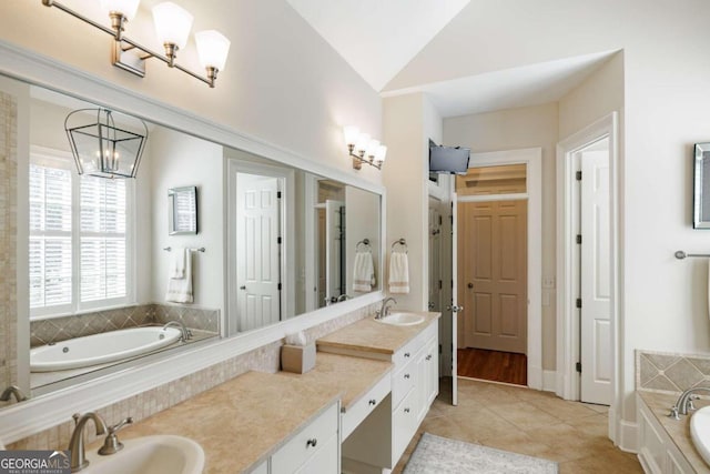 bathroom with tiled tub, tile patterned flooring, lofted ceiling, and vanity