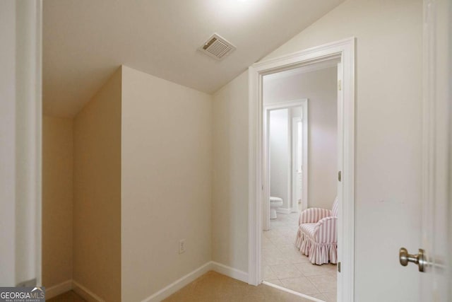 hallway featuring light tile patterned flooring and lofted ceiling