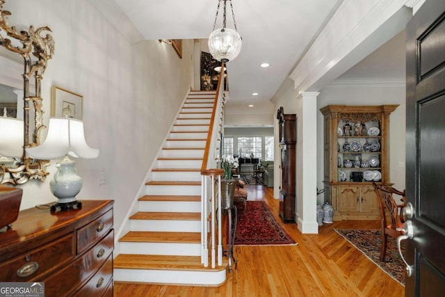 stairway featuring ornate columns, hardwood / wood-style flooring, and crown molding