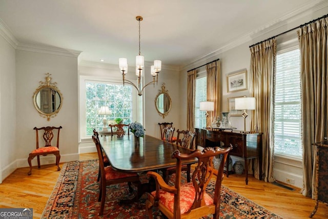 dining space with an inviting chandelier, crown molding, and light hardwood / wood-style floors