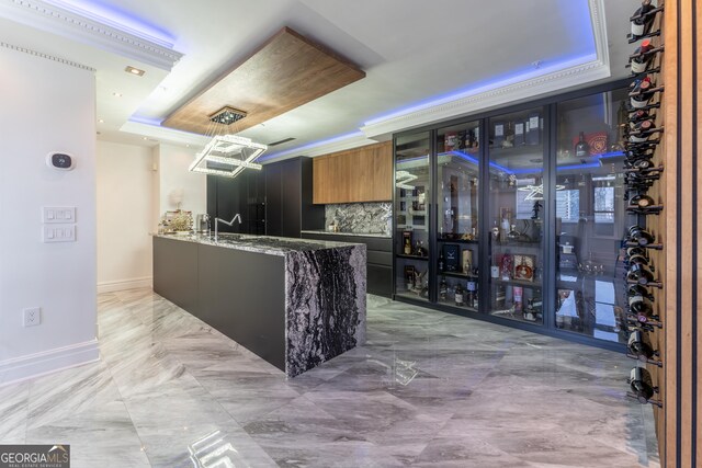kitchen with dark stone countertops, baseboards, decorative backsplash, a raised ceiling, and a chandelier
