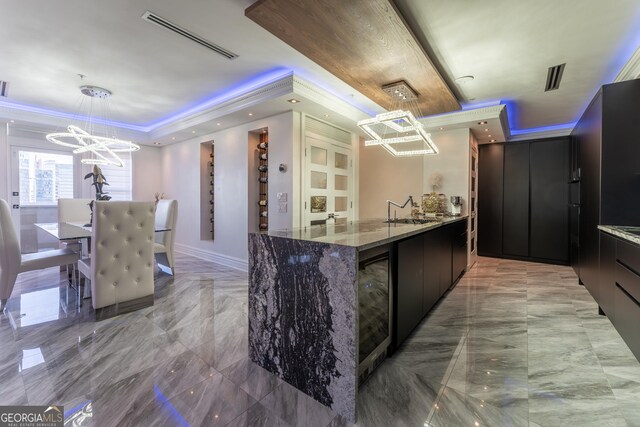 kitchen featuring visible vents, a sink, a raised ceiling, a notable chandelier, and modern cabinets