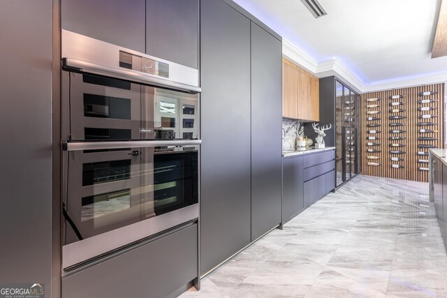 kitchen featuring modern cabinets, double oven, crown molding, and tasteful backsplash